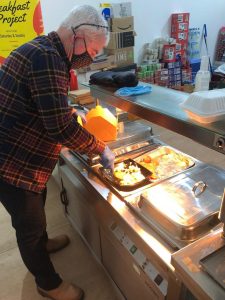 Lifeshare volunteer serving hot food during the Breakfast provision